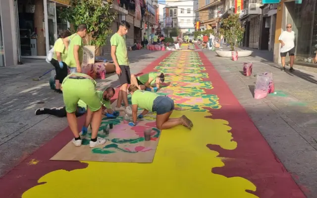 Voluntarios elaboran una alfombra de sal teñida en la calle Aduana de Puertollano para el paso de la Virgen de Gracia